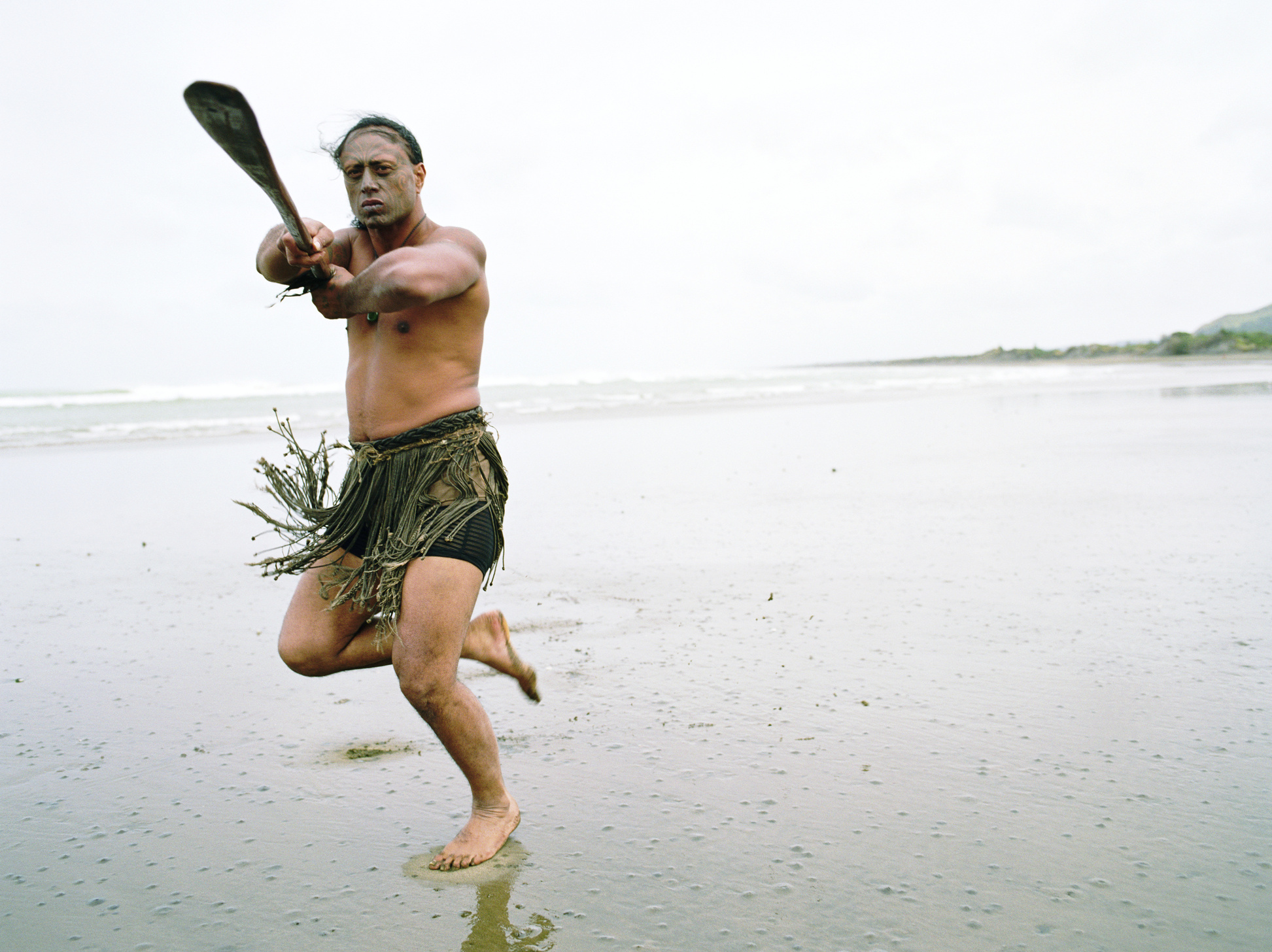 Maori man performing Haka Powhiri on beach