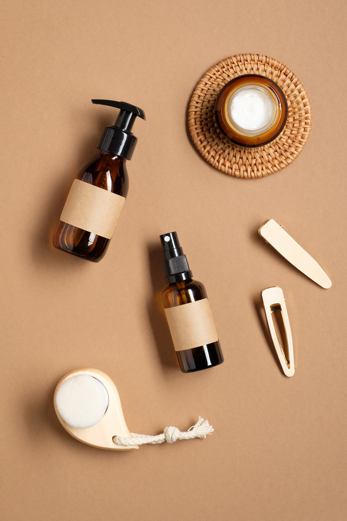 Set of natural cosmetics for skin care in amber glass packaging and female accessories on brown background. Natural beauty product for bathroom. Flat lay, top view.